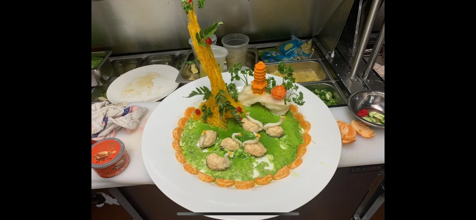 Swan-carved seafood dish over green sauce